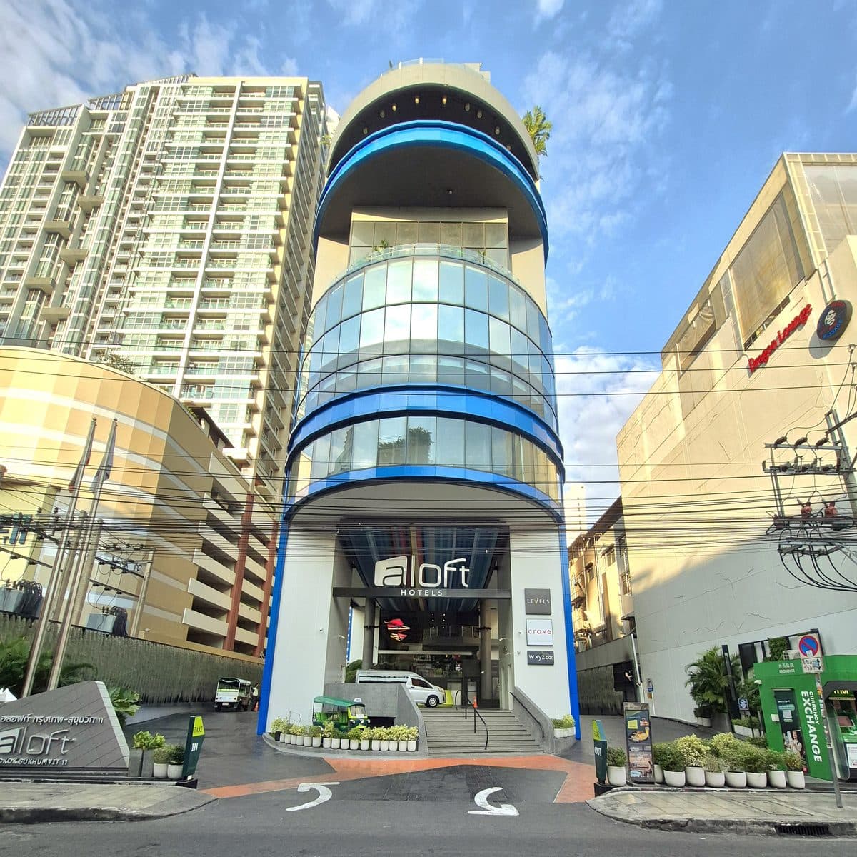 スクンビット Soi 11 に建つ Aloft Bangkok の正面。青いラインの入った曲面のガラス棟と、車寄せの上の aloft の看板