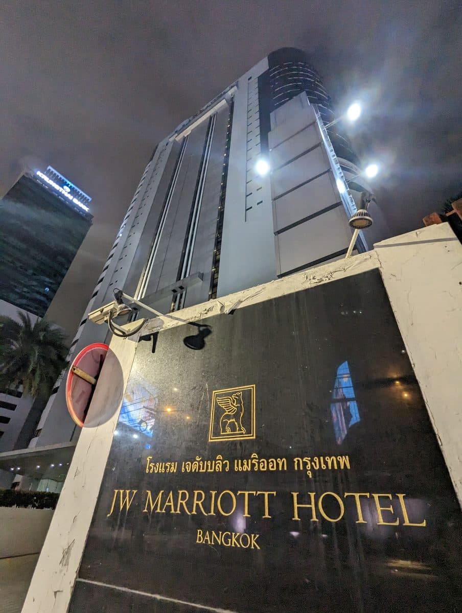 夜の JW Marriott Hotel Bangkok。手前に金文字の看板、奥に見上げる形で客室棟